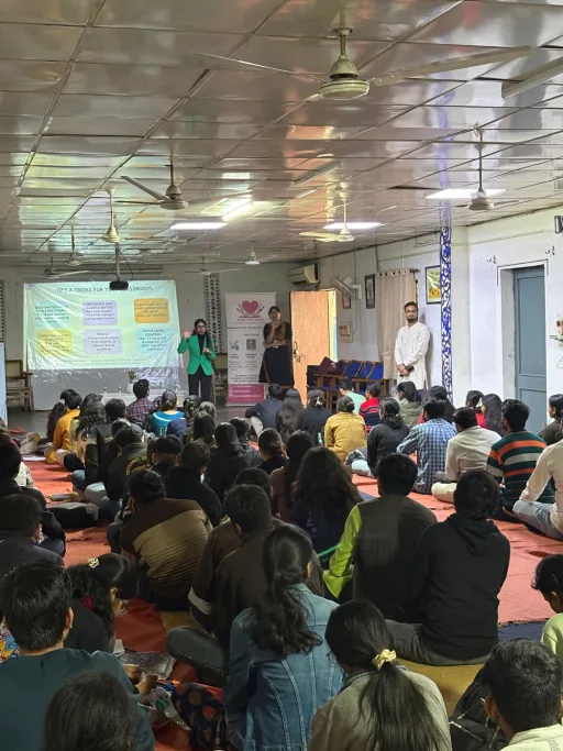 A group of university students gathered around the Heart Arts India banner at the end of a campus session
