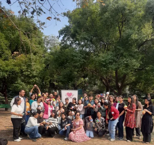 A Heart Arts facilitator outdoors with two young girls holding the paper hands they cut out